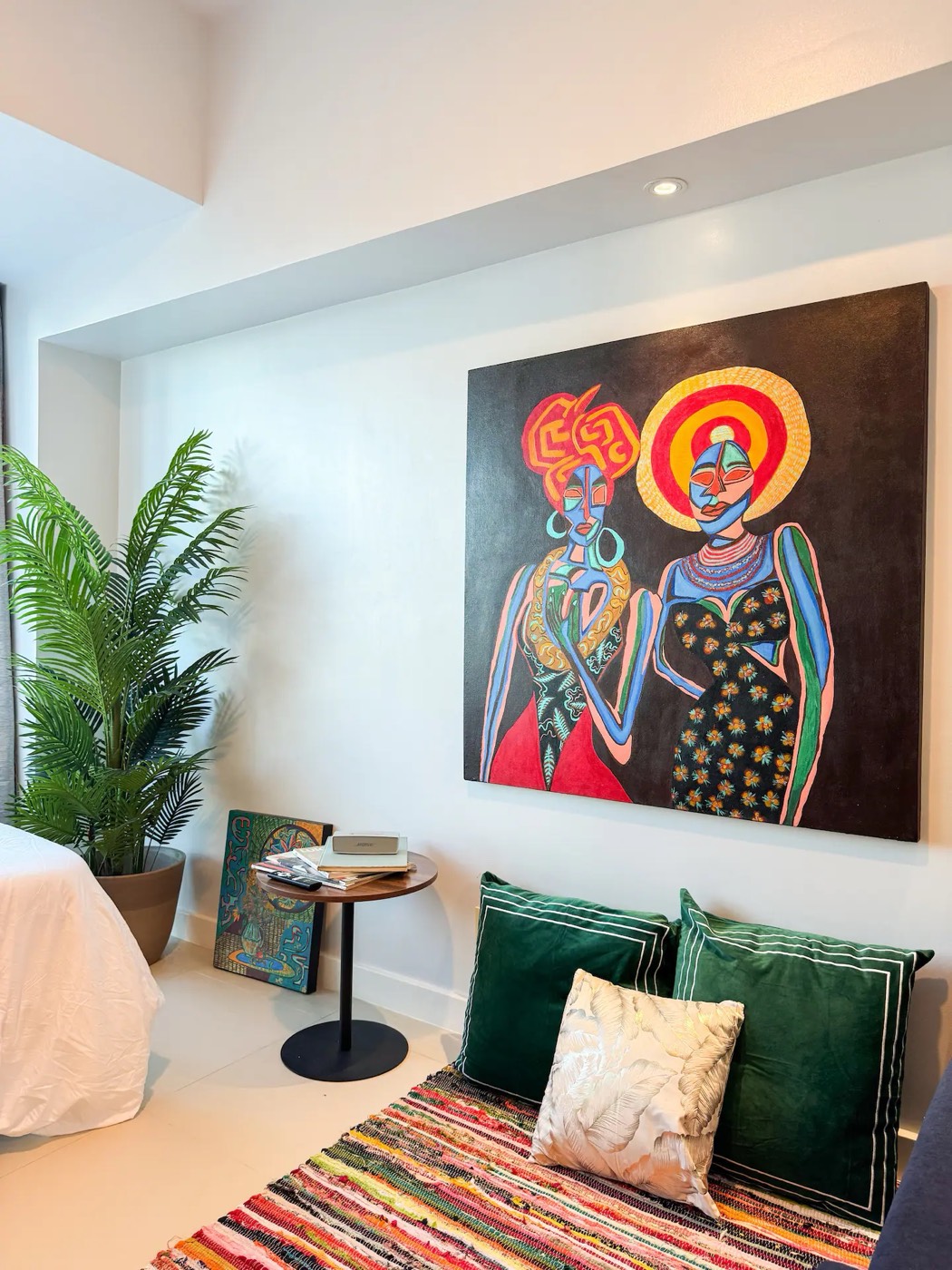 An original painting hanging in Estudio La Vida, above a round table and a plant, with the studio's seating to one side.