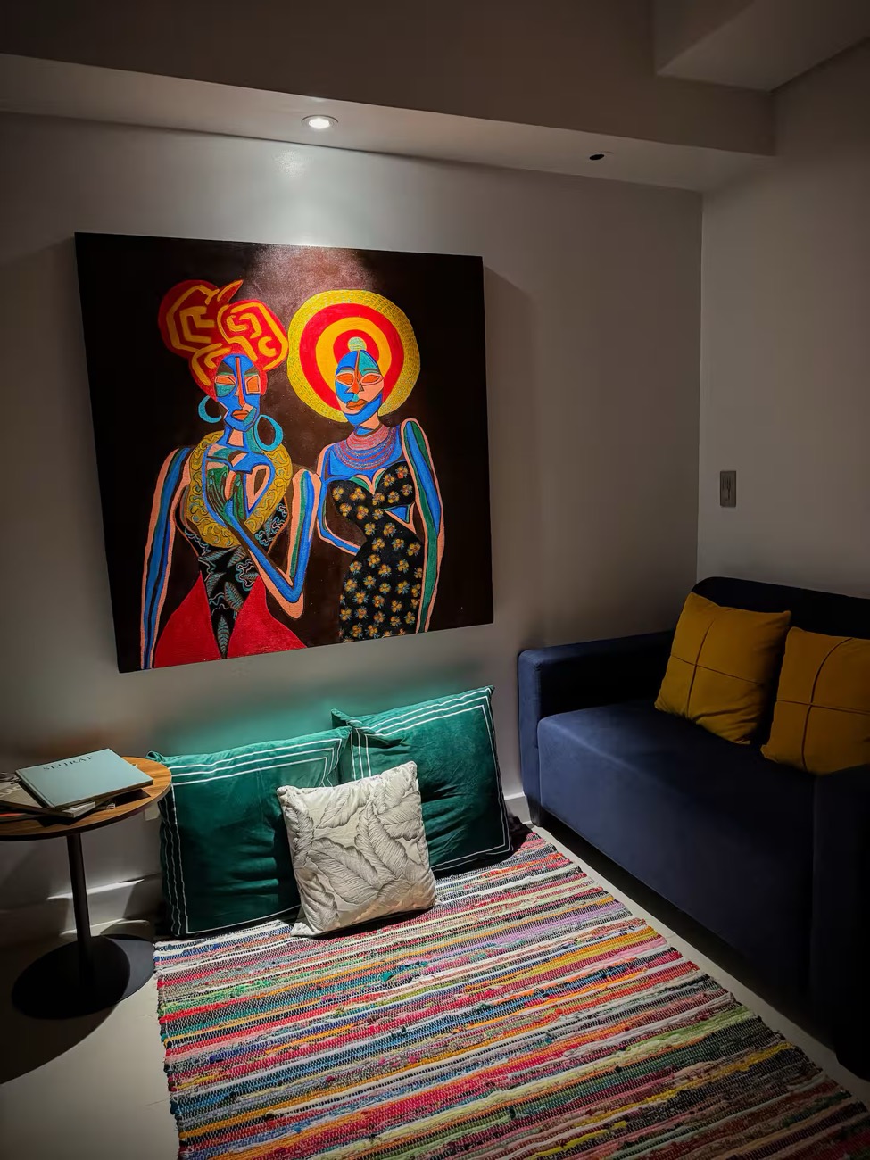 Estudio La Vida: a navy sofa and green cushions beneath a large figurative painting.
